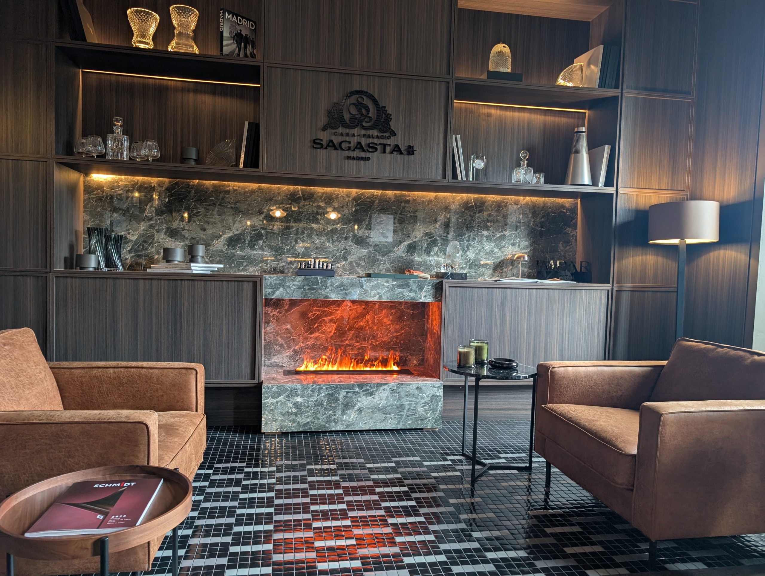 Salón moderno con chimenea de piedra, mobiliario cálido y luz tenue en Casa Decor 2025